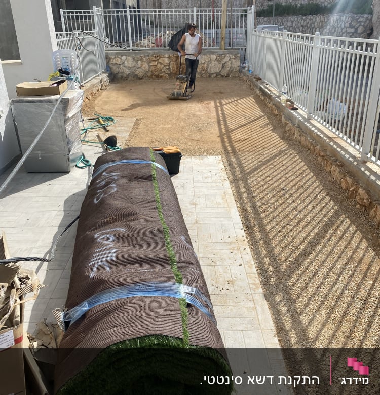 הנחת דשא סינתטי בחצר עם כלי עבודה